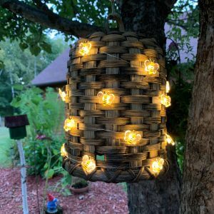 lighted bee hive basket hanging from tree